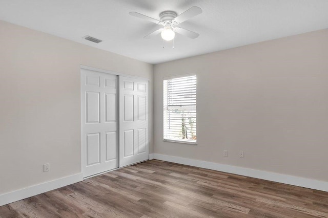 unfurnished bedroom featuring hardwood / wood-style floors, a closet, and ceiling fan