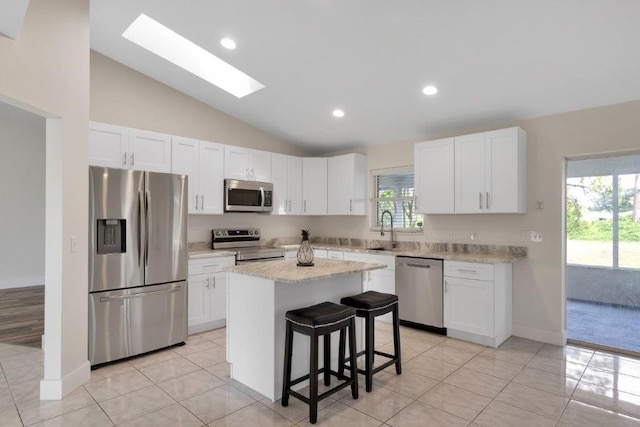 kitchen with a kitchen island, appliances with stainless steel finishes, white cabinets, and a kitchen breakfast bar