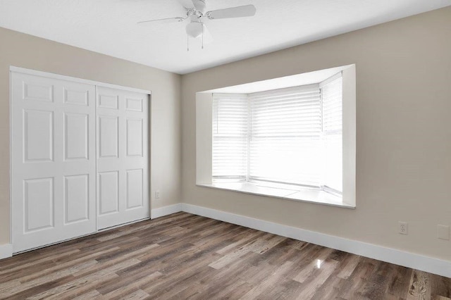 unfurnished bedroom with wood-type flooring, ceiling fan, and a closet