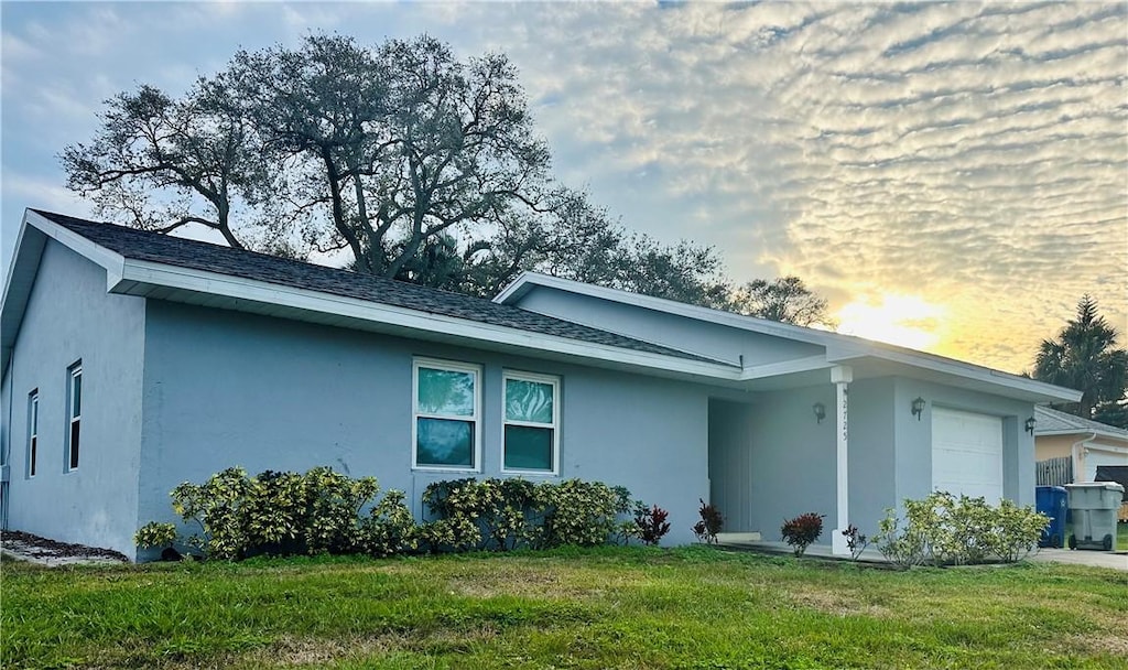 2725 1st Ln, Vero Beach, FL 32968 - property exterior at dusk with a garage and a lawn