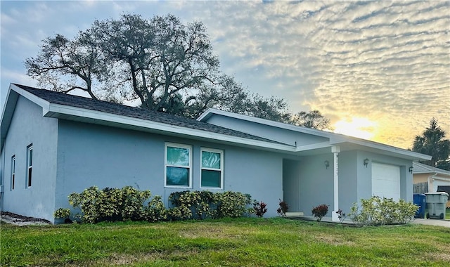 property exterior at dusk with a garage and a lawn