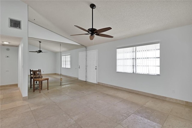 empty room featuring visible vents, lofted ceiling, a textured ceiling, and baseboards