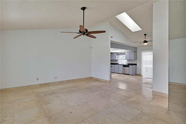 unfurnished living room featuring a textured ceiling, lofted ceiling with skylight, baseboards, and ceiling fan