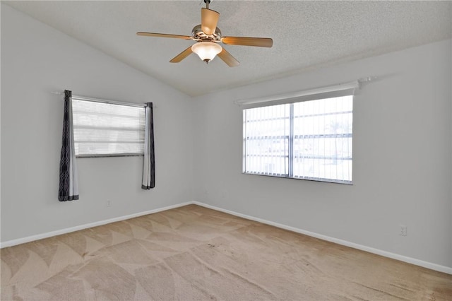 unfurnished room featuring baseboards, ceiling fan, vaulted ceiling, a textured ceiling, and light colored carpet