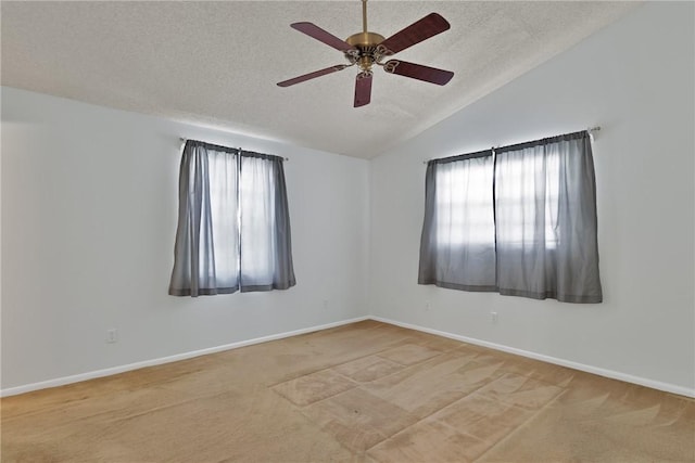 carpeted spare room with vaulted ceiling, plenty of natural light, baseboards, and a textured ceiling