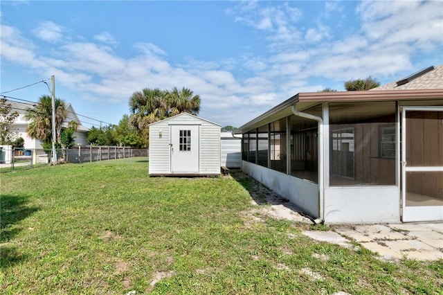 view of yard featuring a storage shed, fence, an outdoor structure, and a sunroom