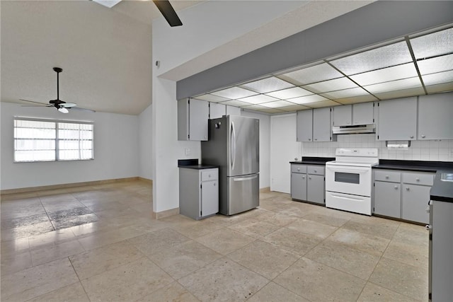 kitchen featuring under cabinet range hood, dark countertops, freestanding refrigerator, and electric stove