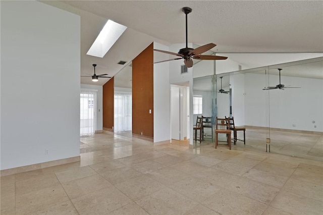 spare room with a skylight, baseboards, visible vents, and high vaulted ceiling