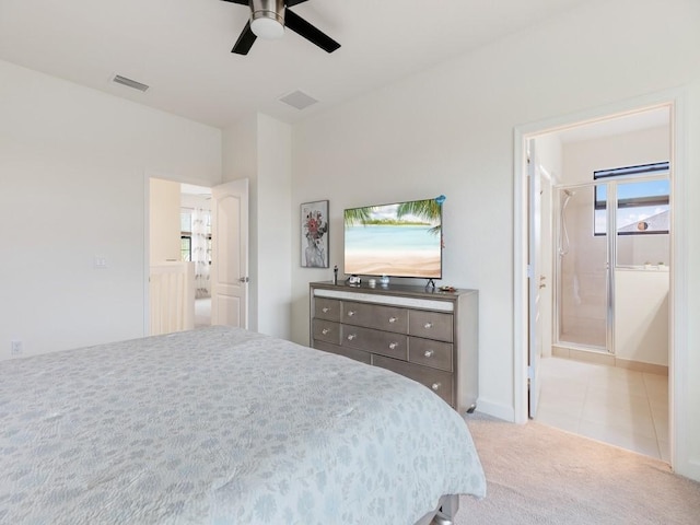 bedroom with ceiling fan, ensuite bathroom, and light carpet