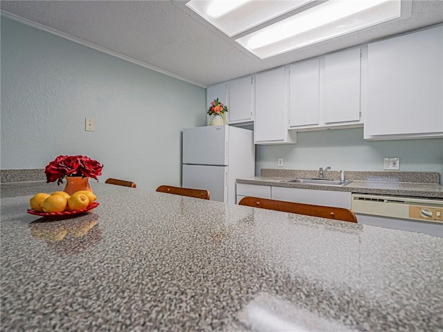 kitchen with white appliances, white cabinets, ornamental molding, a sink, and a textured ceiling