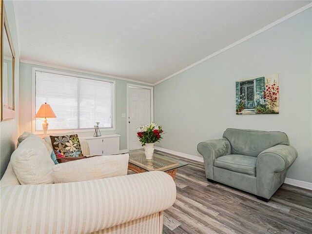living area with baseboards, wood finished floors, crown molding, and vaulted ceiling