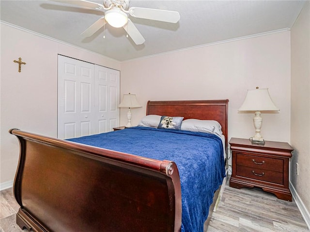 bedroom featuring crown molding, a closet, wood finished floors, and baseboards