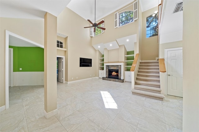 1619 Bent Oak Ln, Vero Beach, FL 32963 - unfurnished living room featuring built in shelves, marble finish flooring, ceiling fan, a fireplace, and a high ceiling