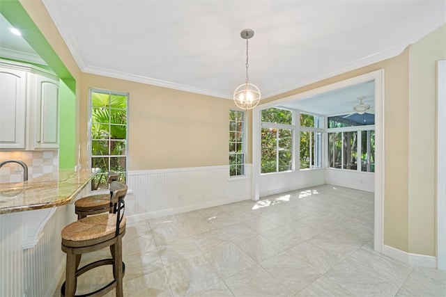 1619 Bent Oak Ln, Vero Beach, FL 32963 - unfurnished dining area featuring healthy amount of natural light, a wainscoted wall, ornamental molding, a sink, and baseboards