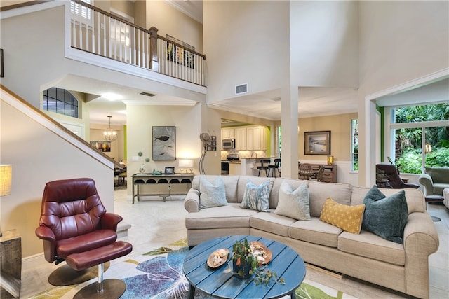 living room featuring an inviting chandelier, a towering ceiling, and crown molding