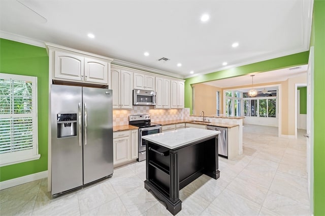 1619 Bent Oak Ln, Vero Beach, FL 32963 - kitchen with stainless steel appliances, a sink, a peninsula, baseboards, and ornamental molding
