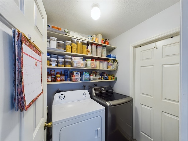 laundry area with independent washer and dryer and a textured ceiling