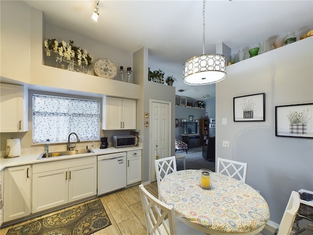 kitchen featuring pendant lighting, dishwasher, white cabinets, and sink