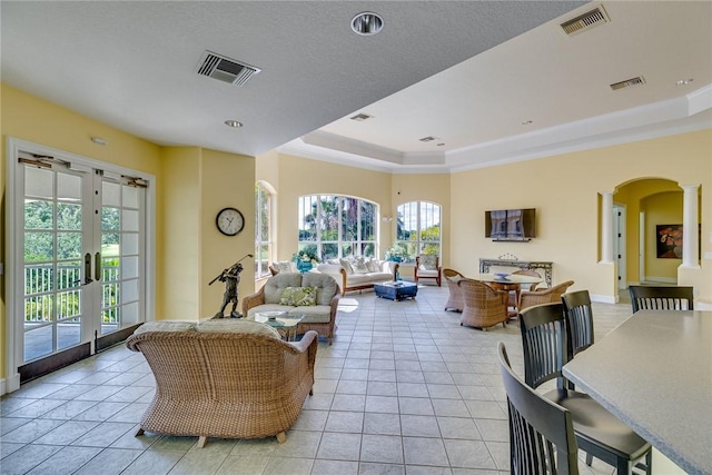 living room with arched walkways, a raised ceiling, and visible vents