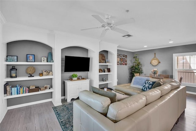 living room with visible vents, crown molding, and wood finished floors