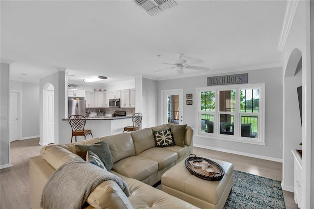 living room with visible vents, wood finished floors, and ornamental molding