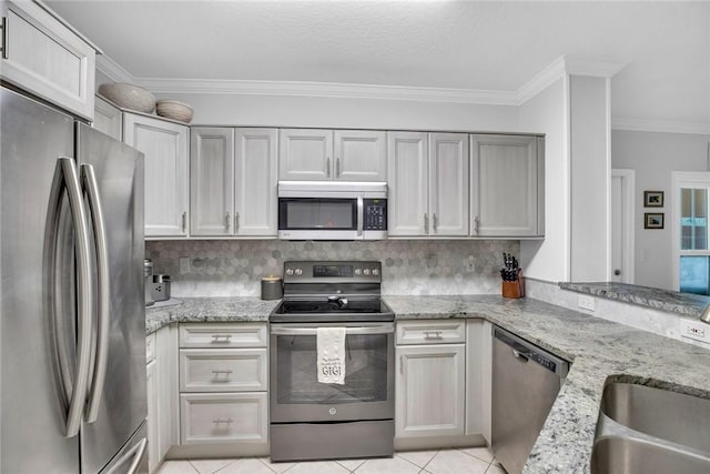 kitchen with light tile patterned floors, appliances with stainless steel finishes, light stone countertops, crown molding, and backsplash