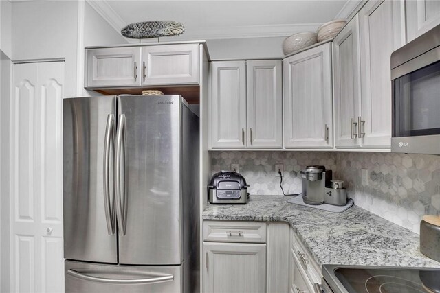 kitchen featuring stainless steel appliances, light stone countertops, crown molding, and tasteful backsplash