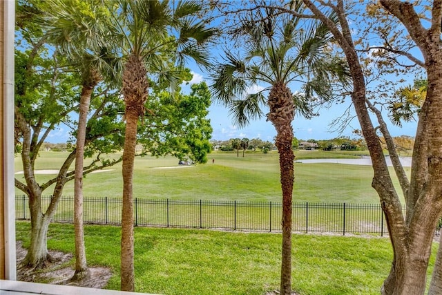 view of yard featuring a water view, view of golf course, and fence