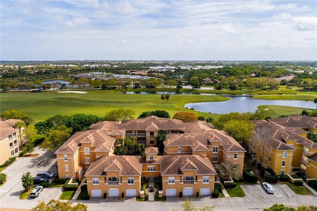 drone / aerial view with view of golf course, a water view, and a residential view