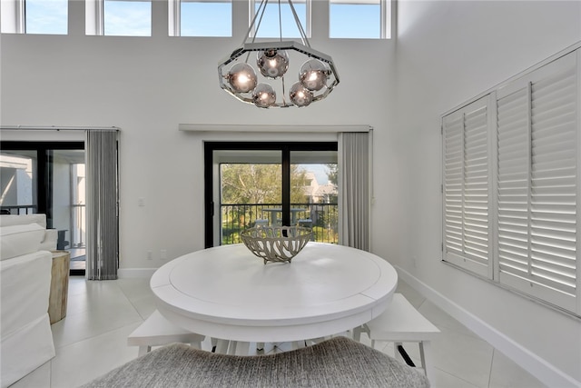 dining area with a chandelier, light tile patterned floors, and a towering ceiling