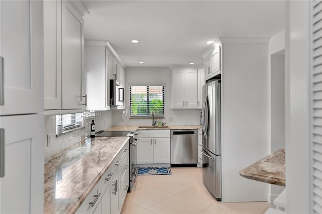 kitchen featuring stainless steel appliances, white cabinetry, sink, and light stone counters