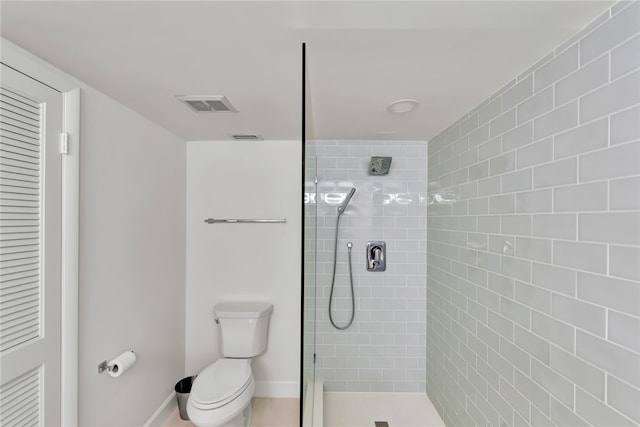 bathroom with a tile shower and toilet