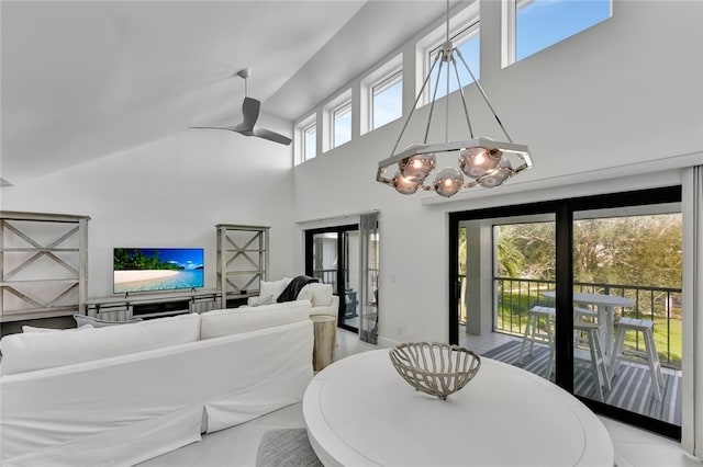 dining room with ceiling fan with notable chandelier, light tile patterned floors, and a high ceiling