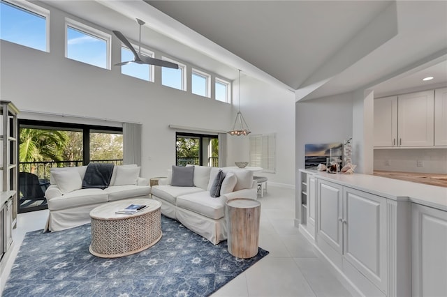 living room with a high ceiling, ceiling fan, a wealth of natural light, and light tile patterned flooring