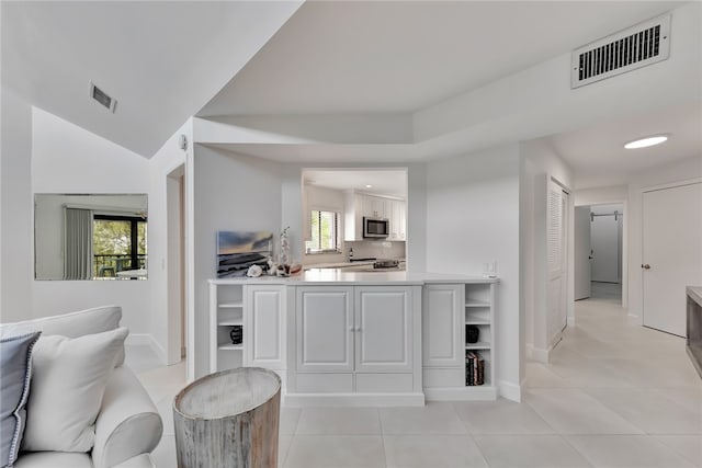 bar with light tile patterned flooring, appliances with stainless steel finishes, decorative backsplash, white cabinets, and lofted ceiling