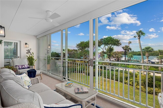 sunroom with a ceiling fan, outdoor lounge area, tile patterned floors, and a water view