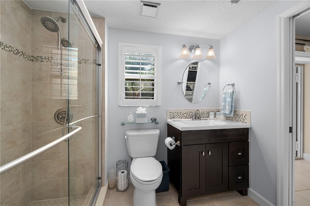 bathroom with a stall shower, tile patterned flooring, vanity, toilet, and a textured ceiling