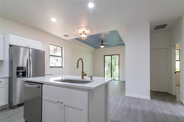 2565 86th Ave, Vero Beach, FL 32966 - kitchen featuring appliances with stainless steel finishes, light wood-type flooring, light stone counters, a kitchen island with sink, and white cabinetry