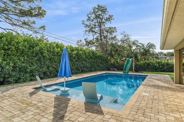 view of pool with a water slide and a patio