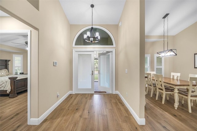 foyer entrance featuring an inviting chandelier, wood-type flooring, and vaulted ceiling