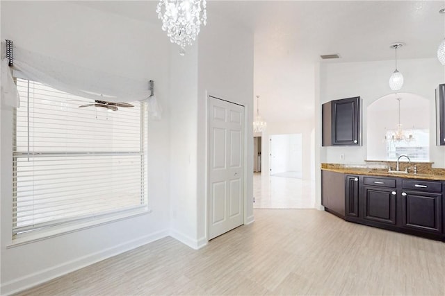kitchen featuring a sink, a notable chandelier, visible vents, light wood-style flooring, and baseboards