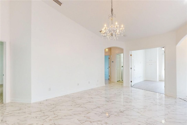 spare room featuring visible vents, arched walkways, a notable chandelier, and marble finish floor