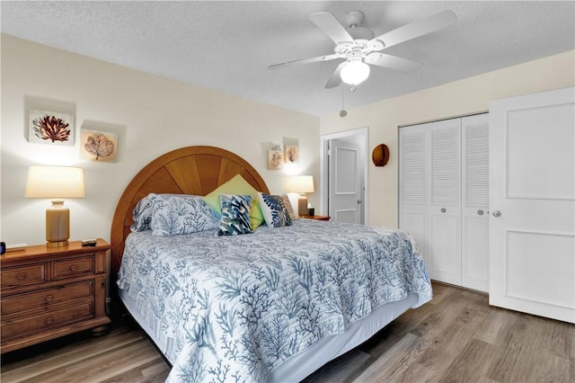 bedroom featuring wood finished floors, a closet, a ceiling fan, and a textured ceiling