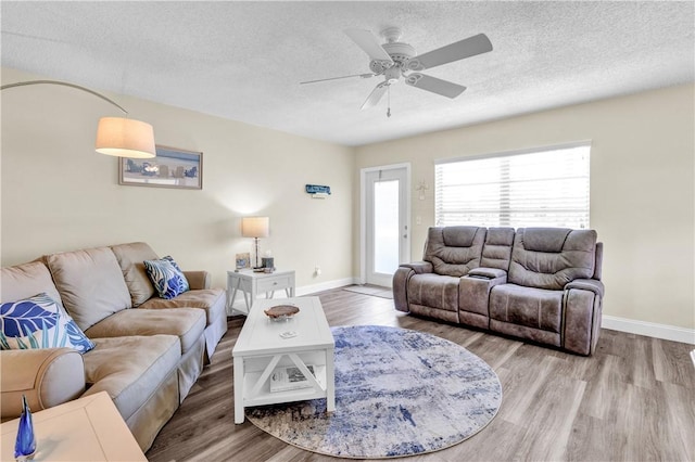living room featuring wood finished floors, a textured ceiling, ceiling fan, and baseboards