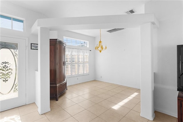 tiled foyer entrance featuring plenty of natural light and an inviting chandelier