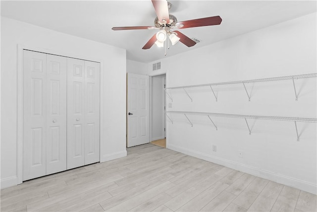 unfurnished bedroom featuring a closet, light hardwood / wood-style flooring, and ceiling fan