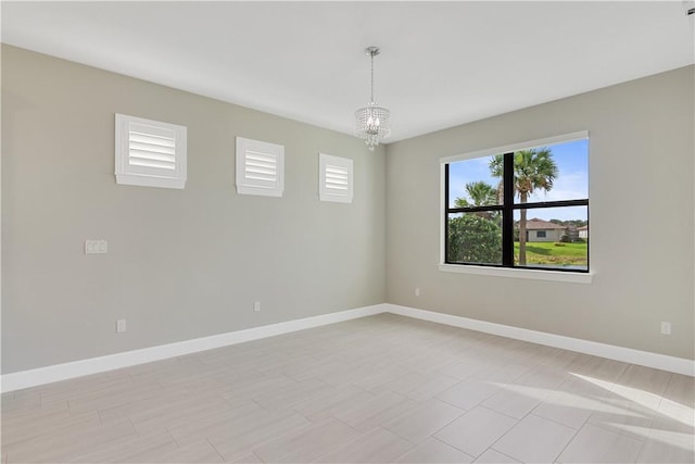 spare room featuring an inviting chandelier and baseboards