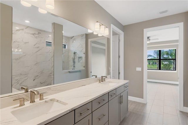 full bath with baseboards, a sink, a marble finish shower, and double vanity