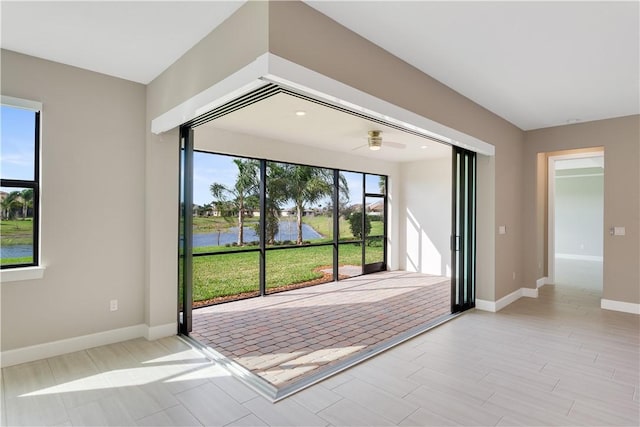 spare room with a water view, light wood-style flooring, and baseboards