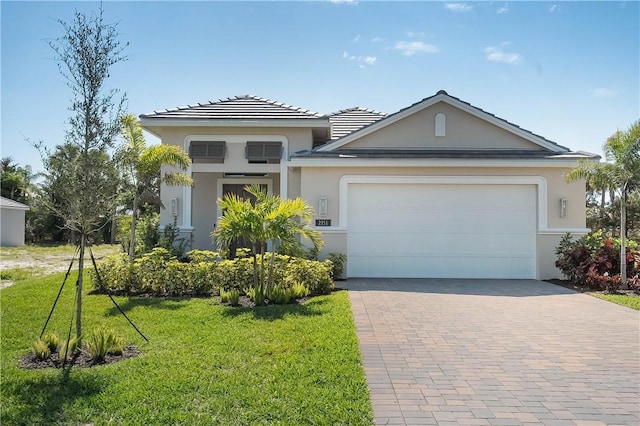 view of front of property featuring a garage, a front yard, decorative driveway, and stucco siding